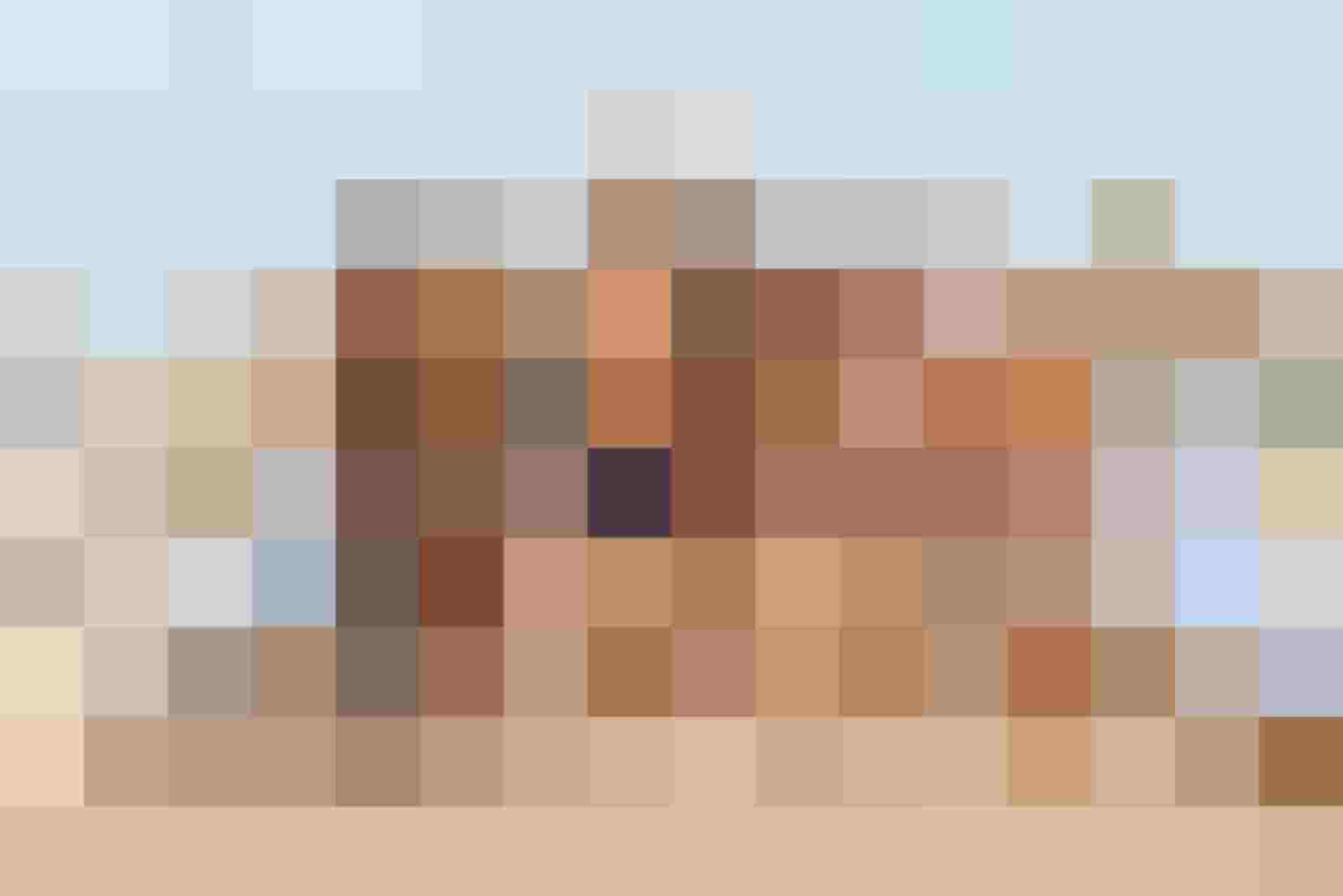 Gruppe von Freunden in Bademode am Strand, lächelnd und fröhlich, mit Sonnenbrillen.