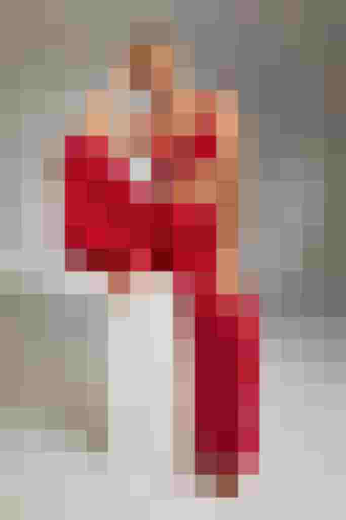 Frau in rotem Spitzen-BH und roter Hose sitzt lächelnd